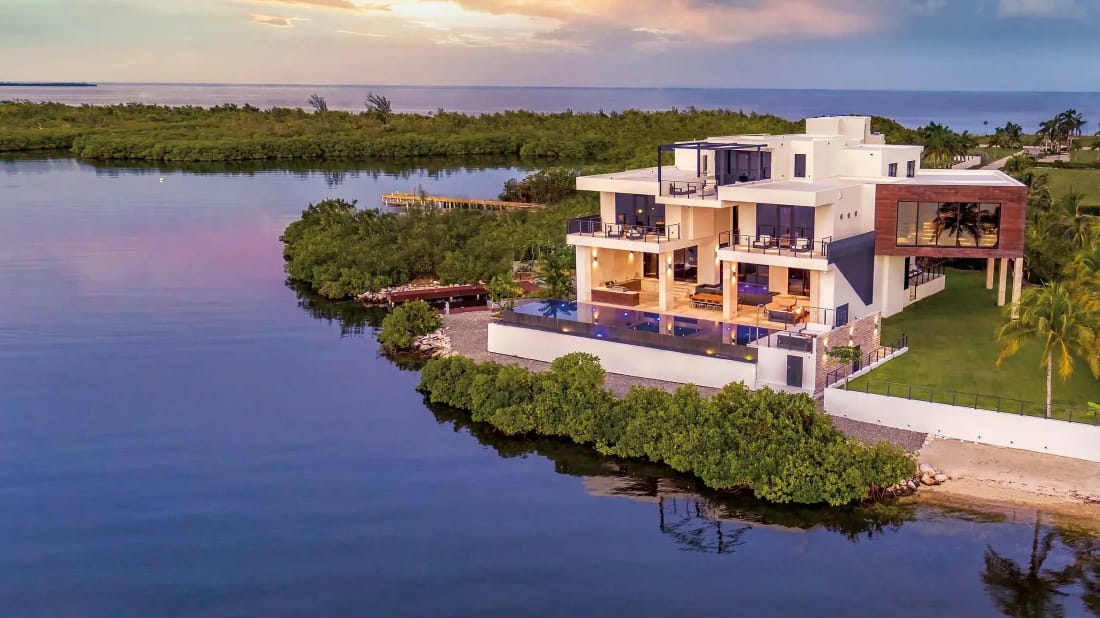 A modern waterfront home with an infinity pool on a Grand Cayman canal at sunset
