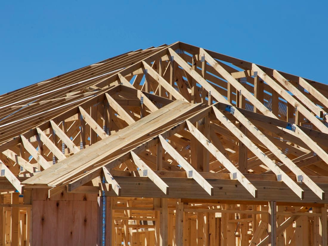 Timber roof framing on a new build against a blue sky